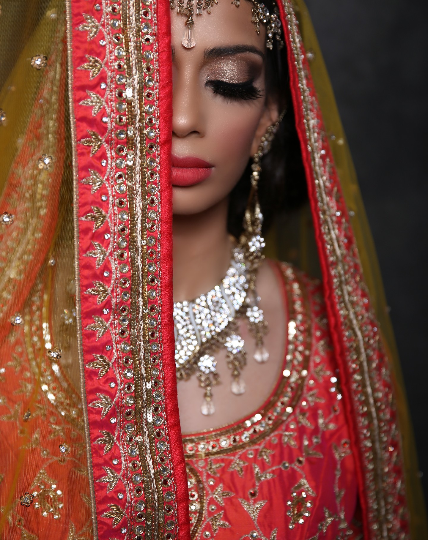 Omar Saleem Photography - Bridal Portrait Photography in Birmingham - Close-up of a bride in a red and gold embroidered veil, featuring heavy jewelry and gold bridal makeup.