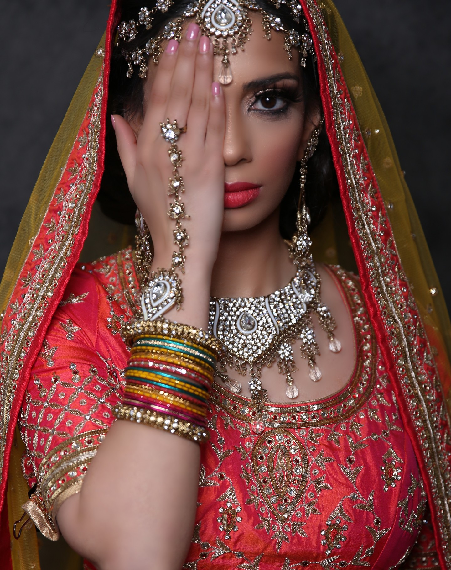 Omar Saleem Photography - Bridal Portrait Photography in Birmingham - Close-up of a bride in a red and gold embroidered veil, featuring heavy jewelry and gold bridal makeup.